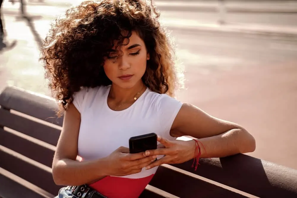 Colombian lady using iPhone 13, checking Facebook, Twitter, email, and various websites reading the latest articles on hard water rinsing.