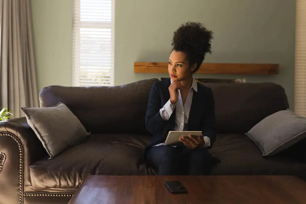 African American woman with long thick hair wearing a messy loose bun with a blue business suit and red lipstick