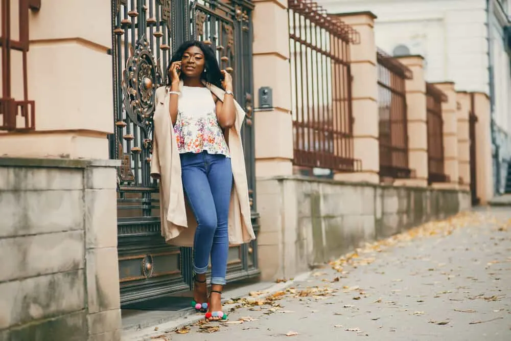 Lady standing outside with jet black hair talking on a mobile phone wearing casual fall clothes