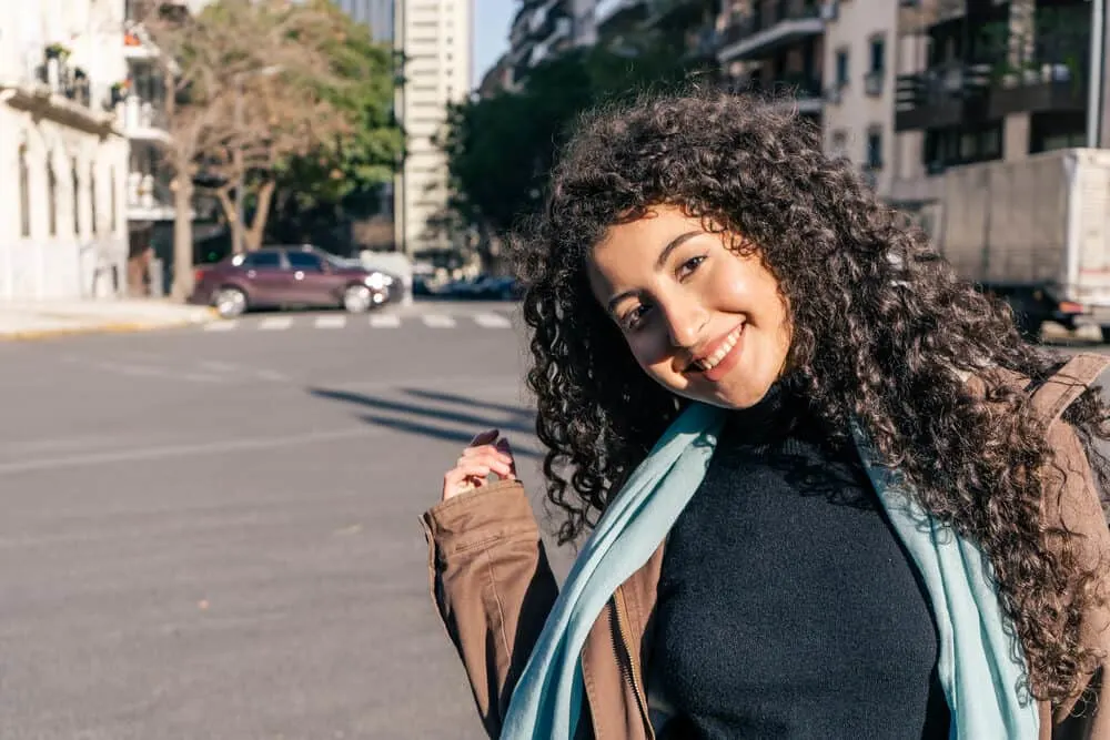 Beautiful young woman with wavy hair walking down the street