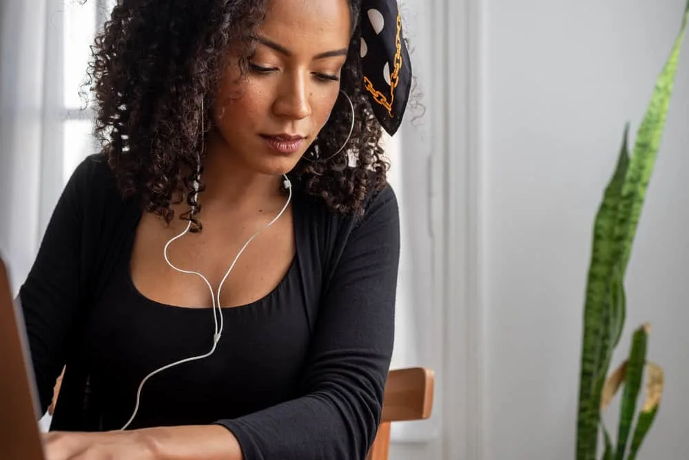 Cute girl using a laptop with earphones wearing a black shirt