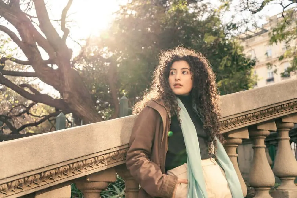 A gorgeous, young, and elegant Hispanic woman is resting on an old concrete staircase