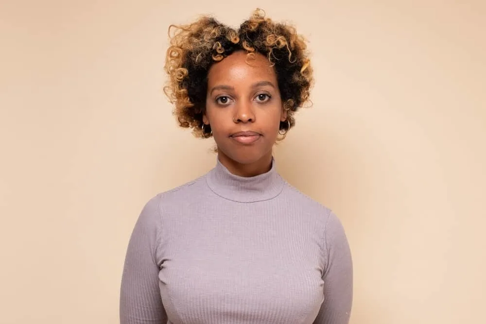 Young African woman with type 4 curls on dark brown hair with yellow-orange tones