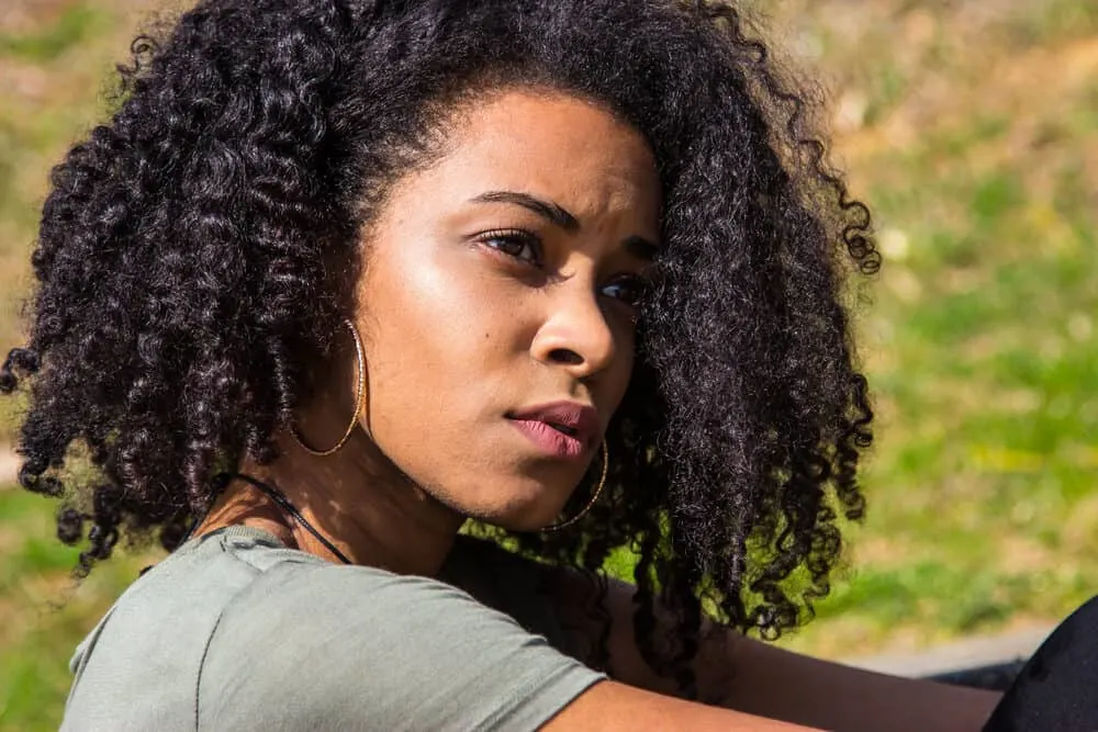 African American lady sitting outside wearing keratin-treated hair with casual clothing