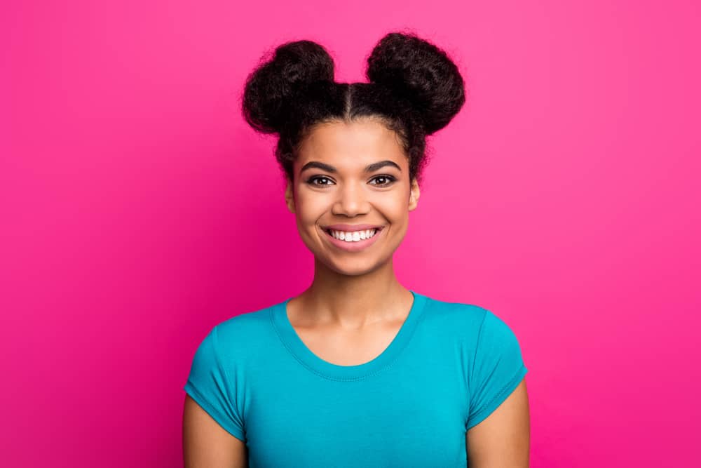 Cute African American female wearing a blue shirt with half-up space buns