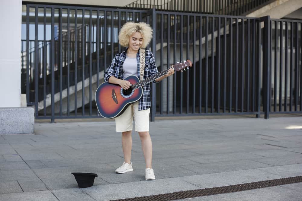  Músico callejero femenino con cabello rubio ceniza claro preparándose para actuar en un concierto