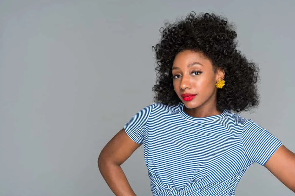 Black girl wearing a blue and white t-shirt, red lipstick, gold earrings, and a natural black hair color