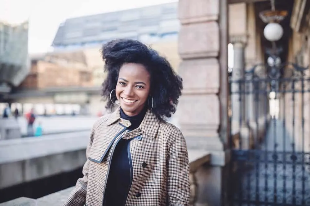 African American female with healthy hair wearing a plaid coat and hoop earrings