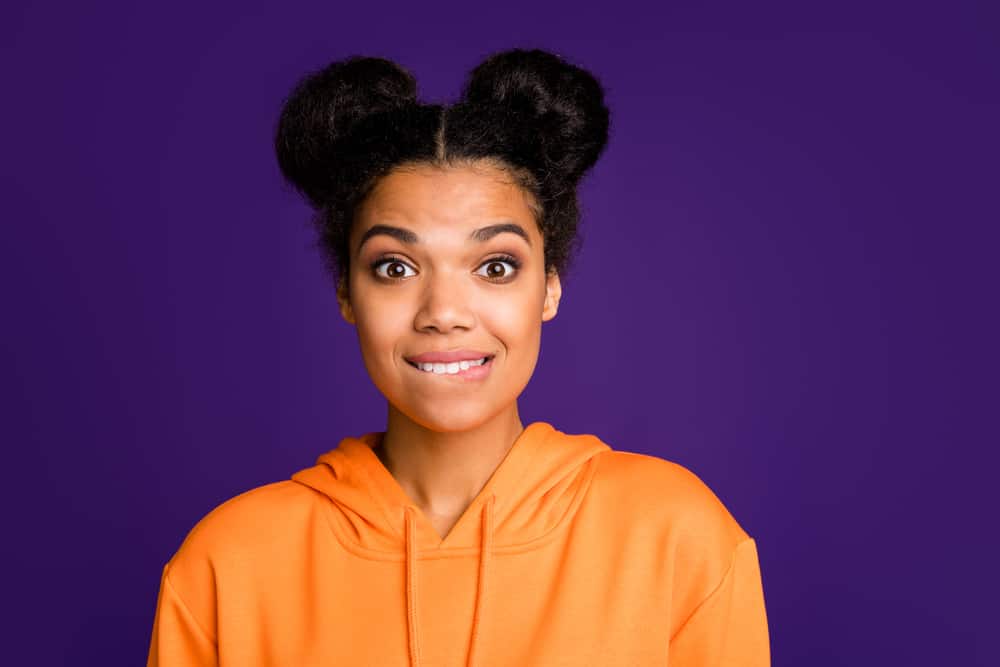 Black girl wearing a hoodie looking nervous while wearing a space bun style