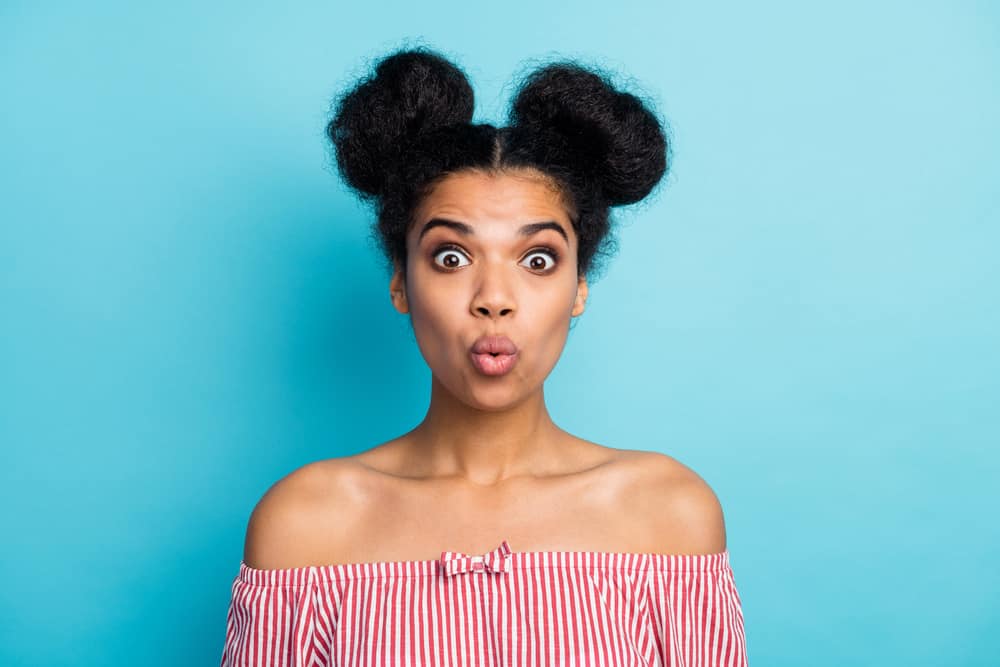 Female with a surprised look wearing a red and white shirt with double buns 