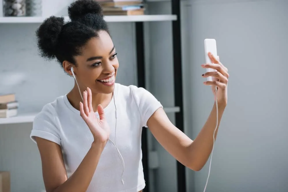 The young black lady taking a selfie with two puffs on thick, curly short hair