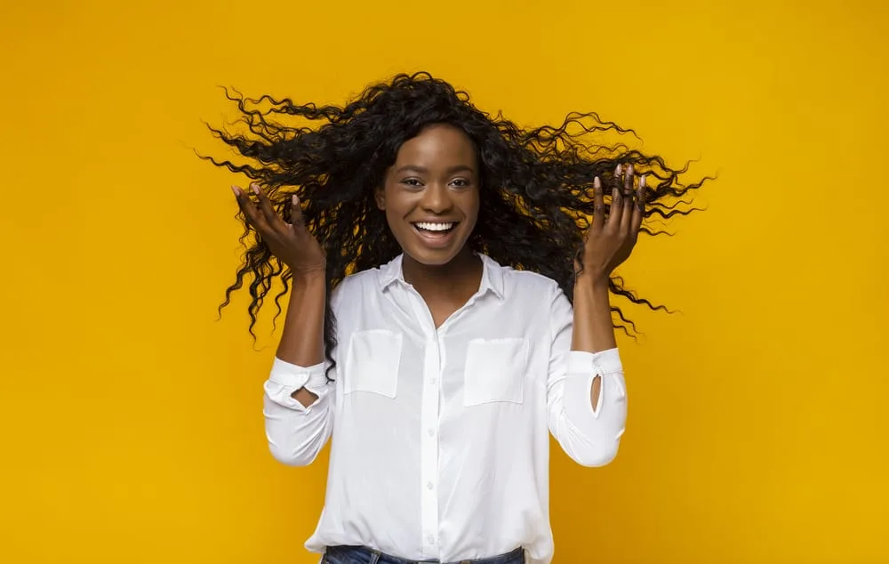 A cheerful black girl with a curly weave texture