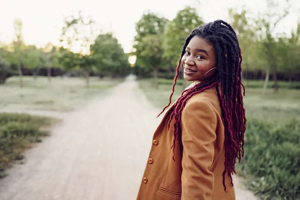 Stylish African American lady walking down a dirt road with her hair unraveling