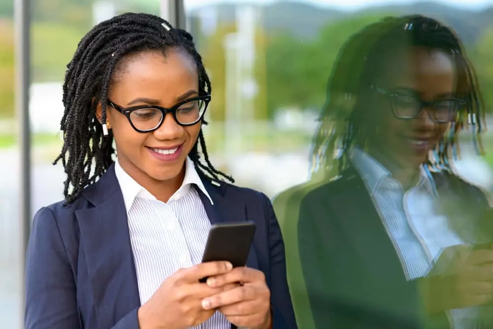 Lady using a cell phone with teen stage faux locs reading about the five stages of locs