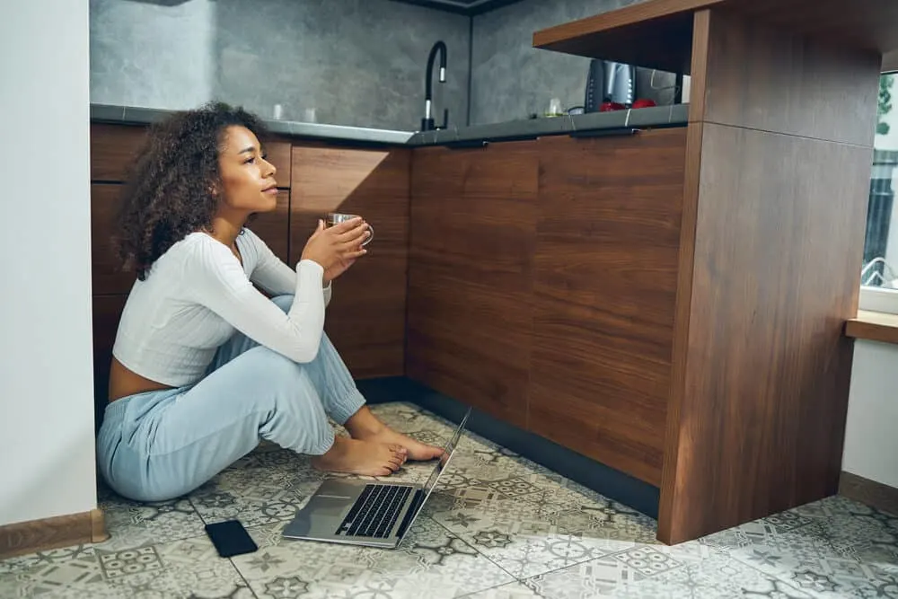 A thoughtful young lady sitting on the kitchen floor thinking about the right and wrong way to towel-dry hair