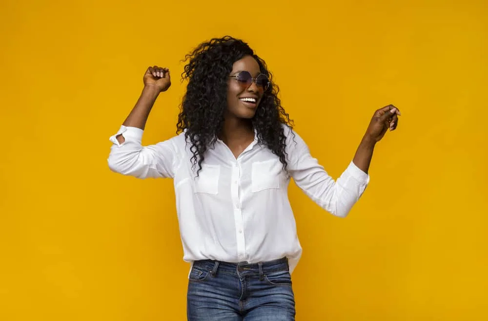 Black woman dancing wearing a combo wavy-straight hair bundle with casual clothes