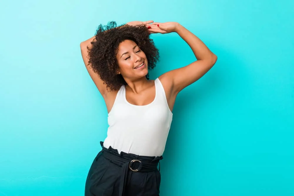 Black lady stretching wearing low maintenance spring hair extensions 