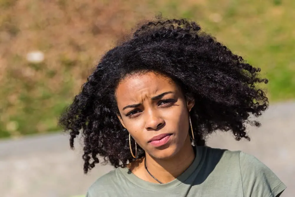 Beautiful black girl with coily frizz-free hair wearing hoop earrings and red lipstick