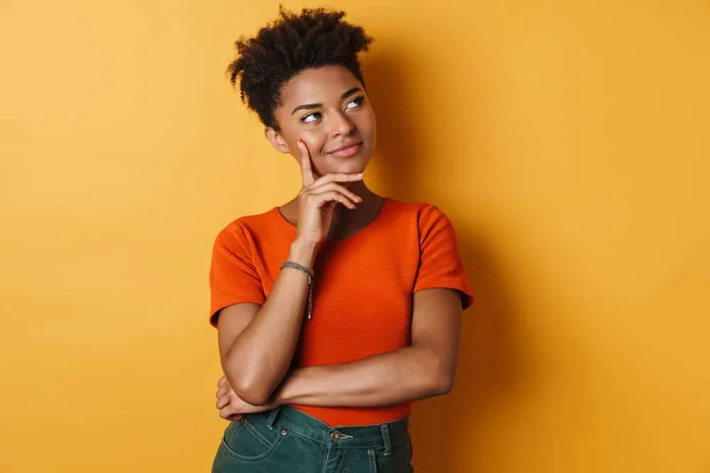 Black woman with a curly hair type wearing casual clothes and looking into the distance