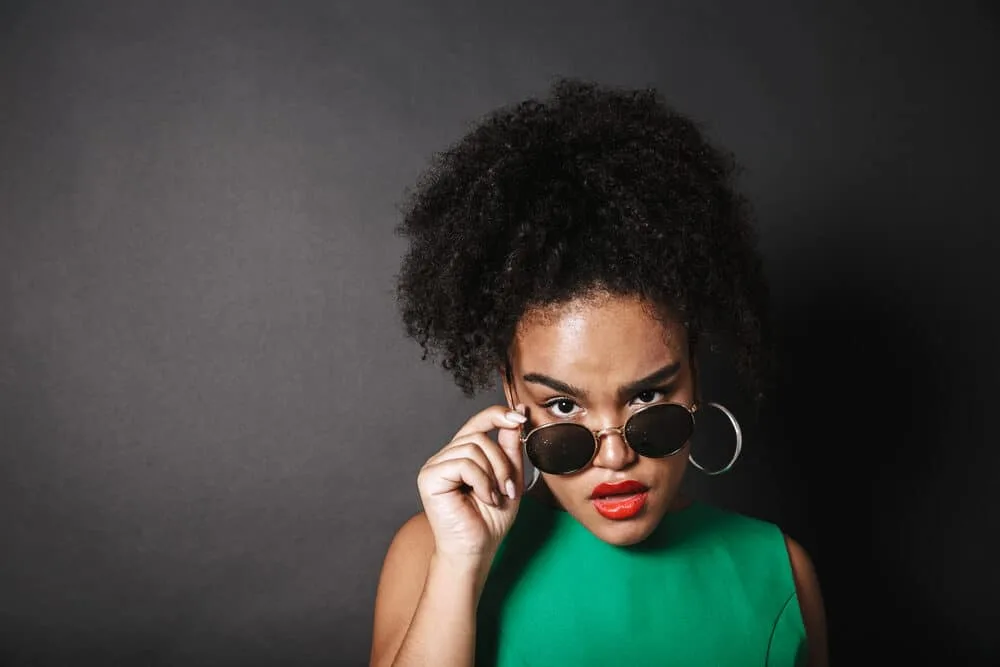 African woman wearing sunglasses with curls in a pineapple hairstyle