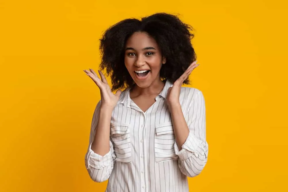 Cute black girl with frizzy hair strands after using a hooded dryer to blow dry her curls