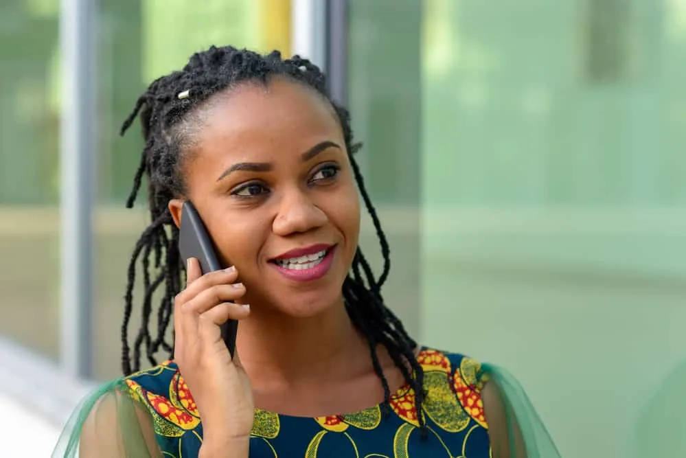 Trendy black woman with dry hair starting loc journey wearing a colorful dress