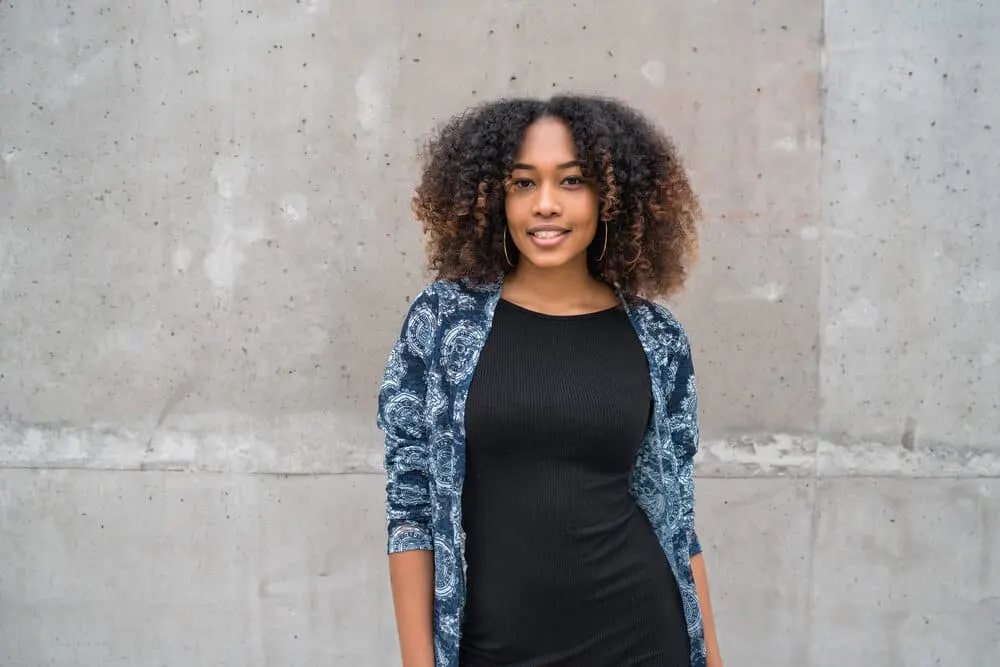 Beautiful black girl with curly dry hair cuticles wearing a black dress