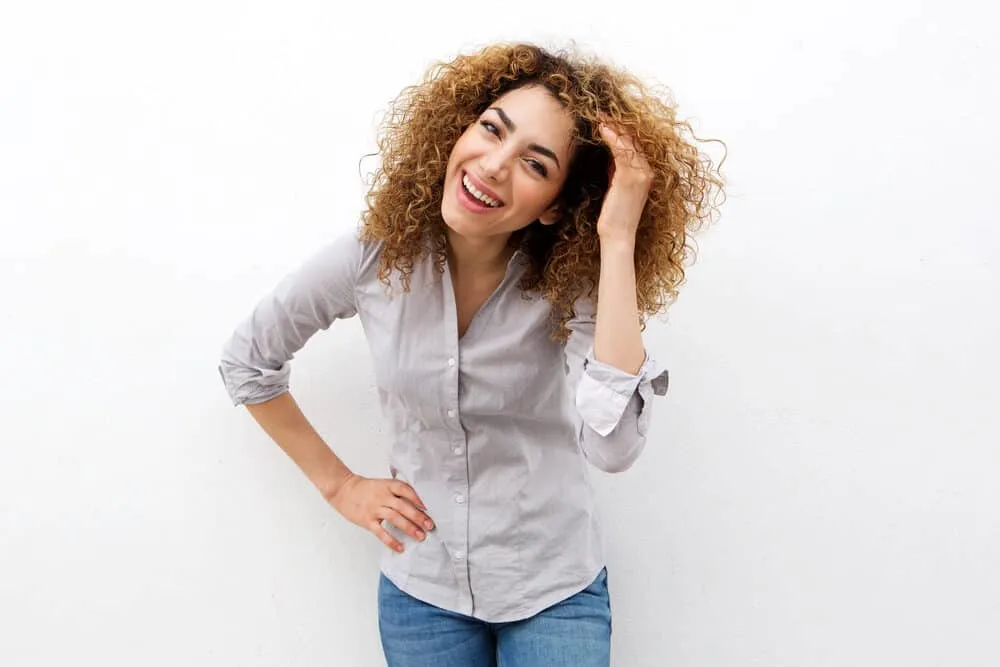 Caucasian woman with bleached hair laughing wearing a gray dress shirt