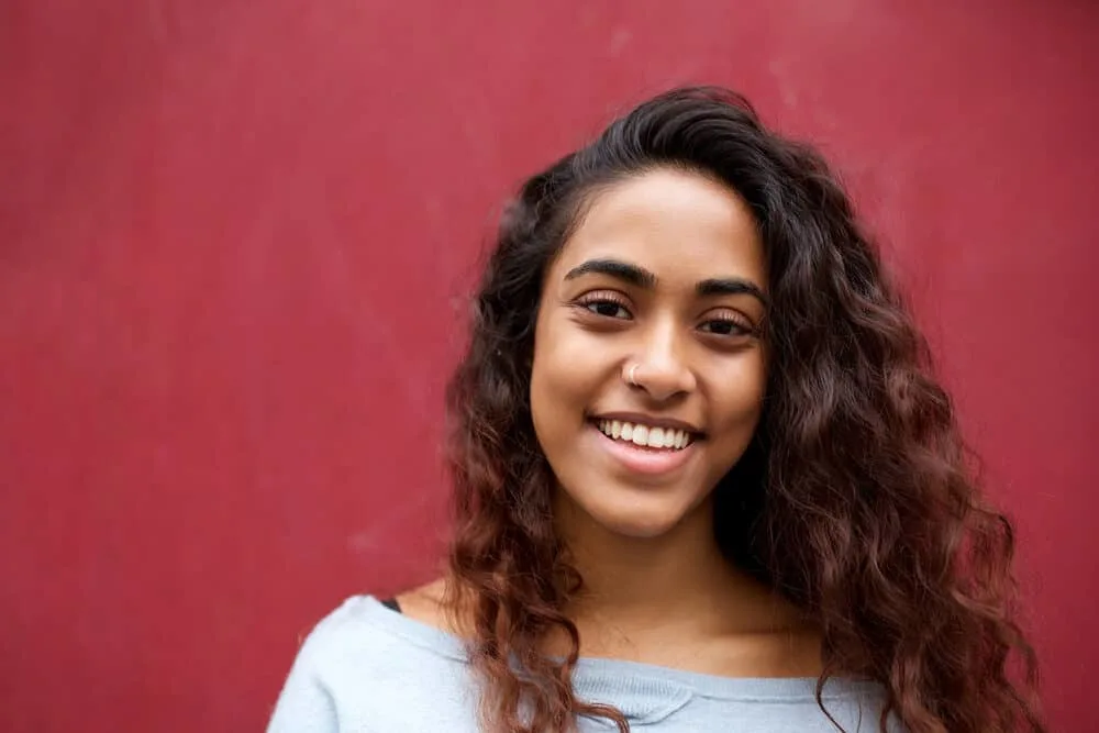 Happy young Indian woman wearing subtle highlights with a caramel balayage