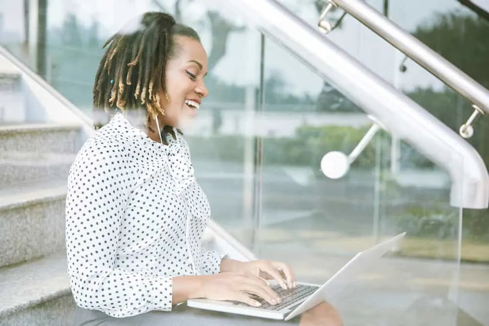 Cute black girl researching how to dye dreads and hide single hair strands on her laptop