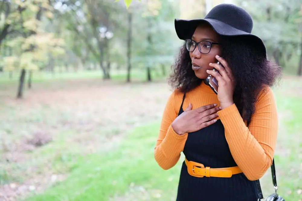 Black woman talking an iPhone 13 to a friend about hair fall and scalp causing dandruff