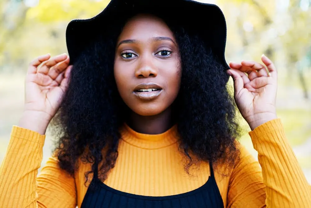 Cute African woman with thicker hair that wearing a black hair and orange shirt