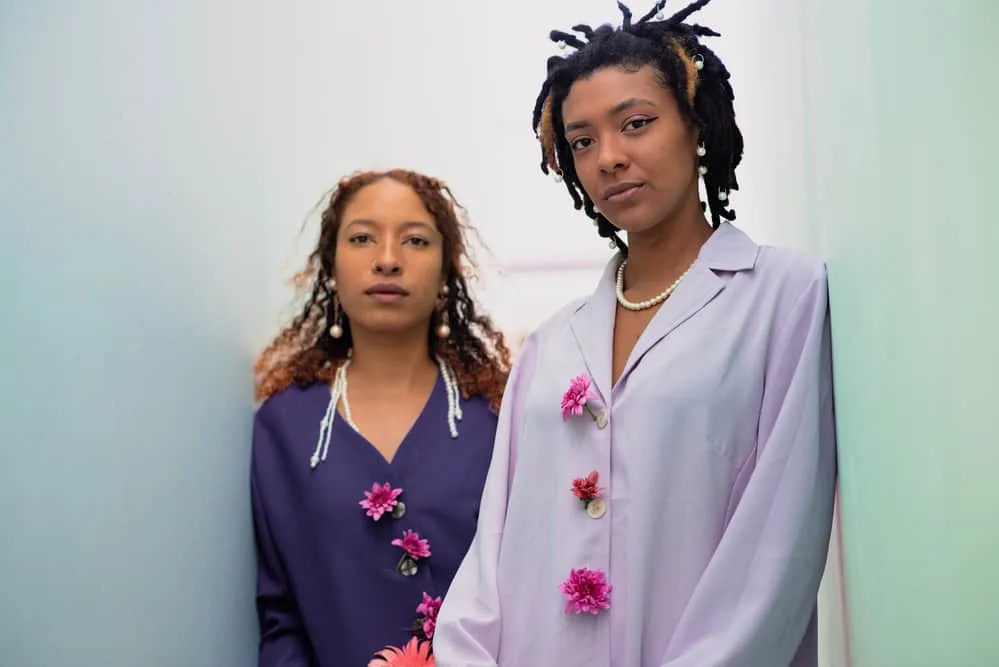 Two young ladies wearing dress clothes adorned with flowers