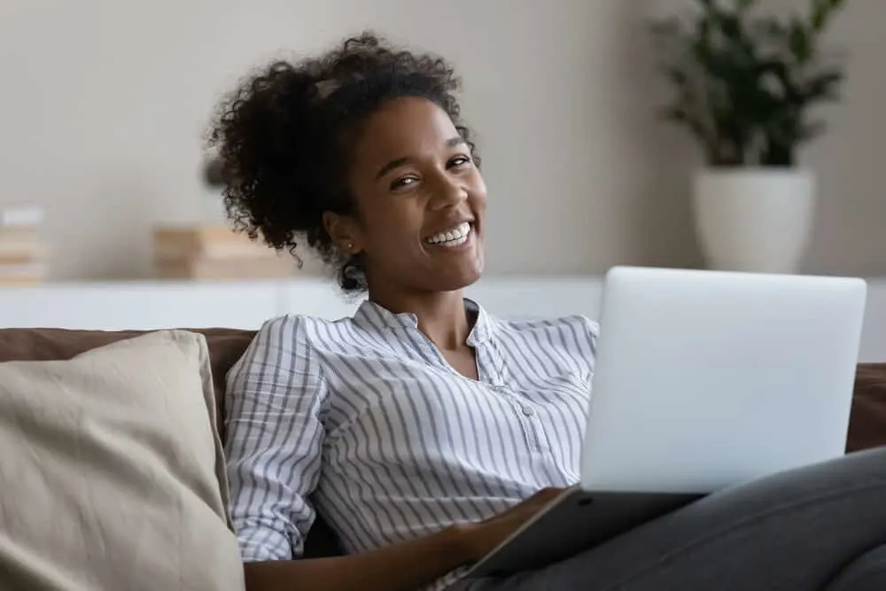 Multiracial woman with sensitive skin sitting on the couch using a laptop