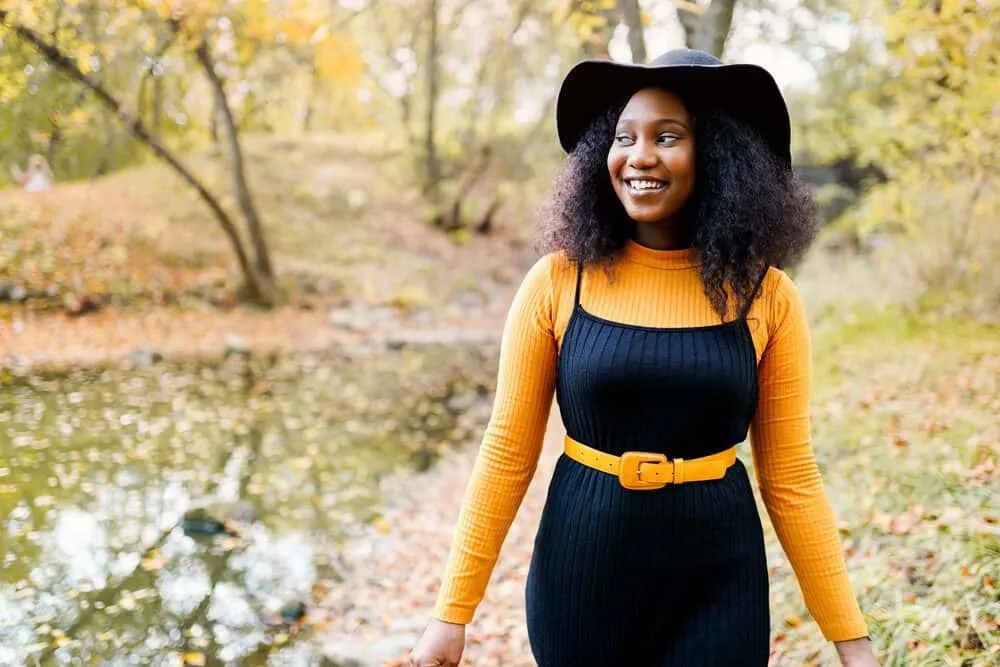 Black woman wearing a black dress with curly healthy hair treated with a good quality pomade