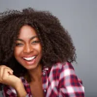 Cheerful African American lady with curly natural hair and extensions from a professional hair stylist.