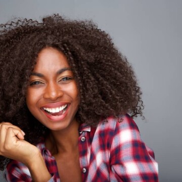 Cheerful African American lady with curly natural hair and extensions from a professional hair stylist.