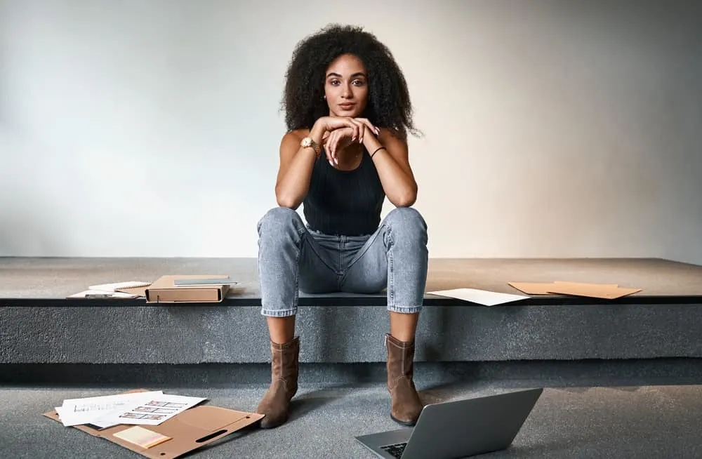 Stunning black female dark brown fragile hair strands wearing a black t-shirt, jeans, and boots