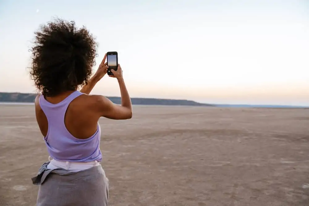 Woman with damaged hair from fraying hair fibers taking a photo from her cell phone at Salt Valley.