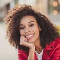 Charming young lady with wavy dry hair dyed brown with semi-permanent hair color wearing a red jacket.