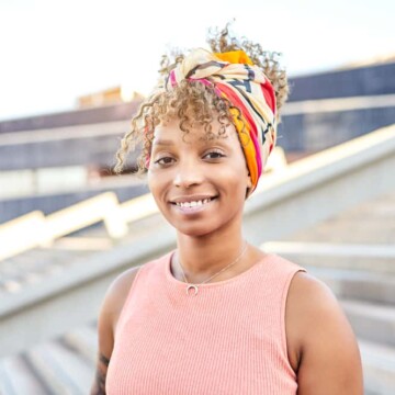 African American lady with a "too" blonde hair color and smooth, cool skin tone wearing a colorful head scarf.