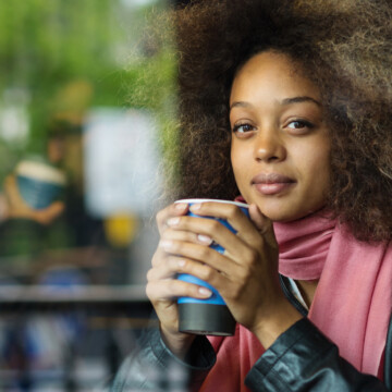 Cute black girl with dark brown hair dyed with black henna drinking coffee.