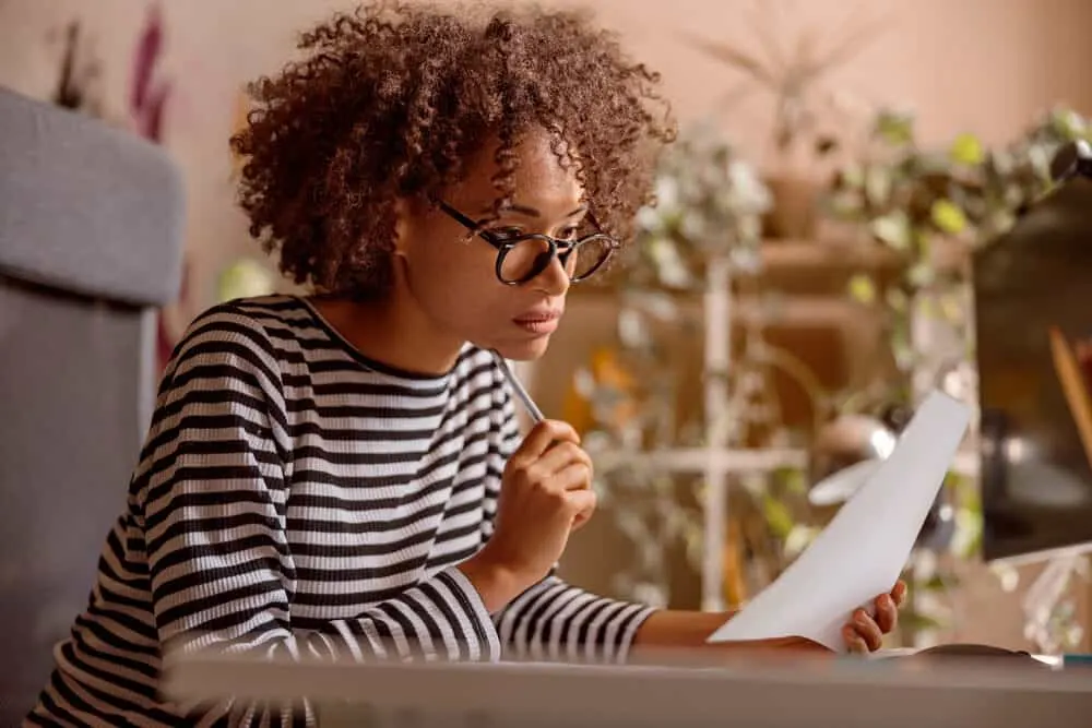 A serious female reading a white paper about how to dye dark or coarse hair with a jello mix.