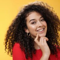 A cute white lady wearing a red shirt with curly permed hair curled with perm rods.