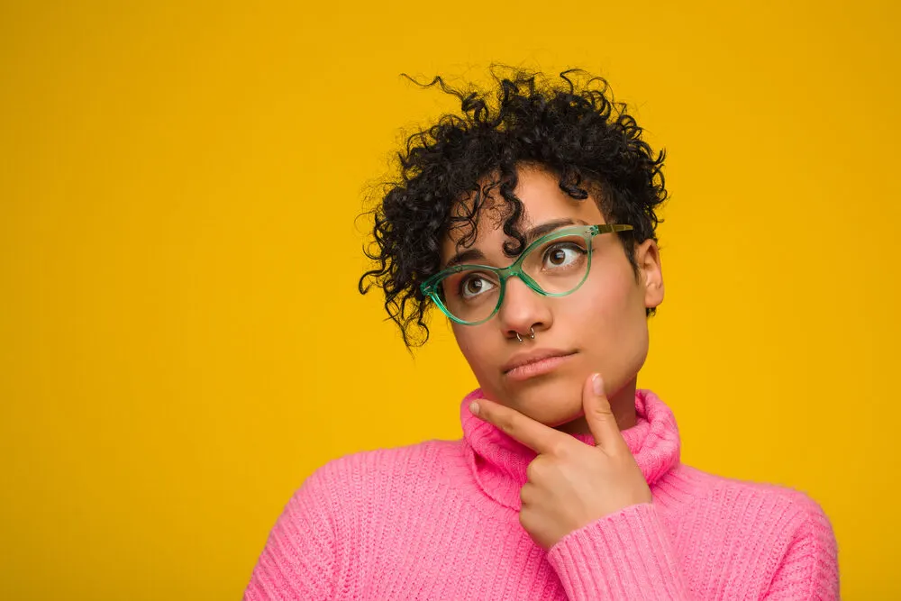 Young African American lady with a light brown natural hair color (or natural hair colour) wearing green glasses.