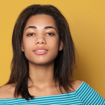 Cute African American female with frizzy hair with curls underneath due to new growth on her kinky hair pattern.