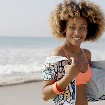 Cute African American female with blonde bleached hair walking in the sand at the beach.