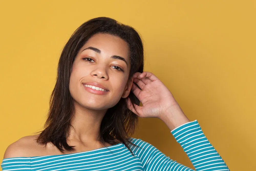 A cute lady with naturally curly long hair that's been straightened wearing blue clothes.