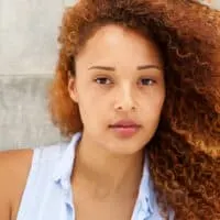 Beautiful mixed-race female with naturally curly hair colored with auburn permanent dye