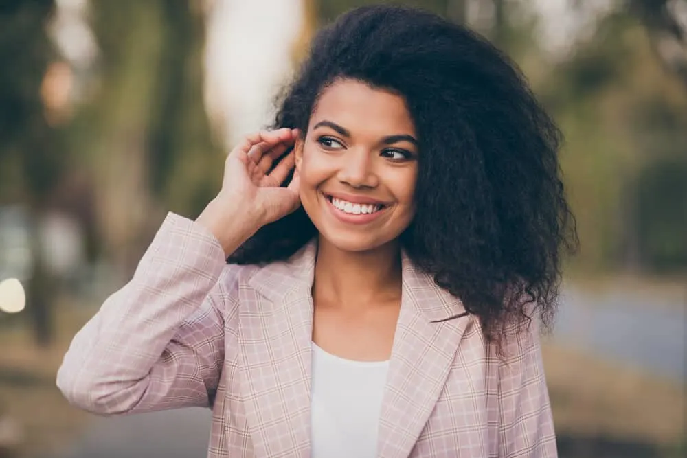 Black woman with curly natural hair that was freshly washed with Dove shampoo.